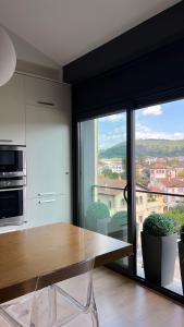 奥洛特Ático de diseño con terraza en el centro de Olot的厨房配有木桌和大窗户。