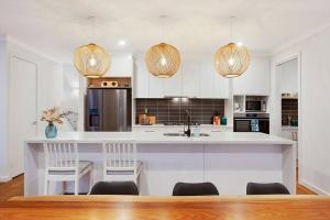 ThebartonLinear Park Living - Brand New 4 Bed Family Home的一间带白色橱柜的厨房和一个带椅子的厨房岛