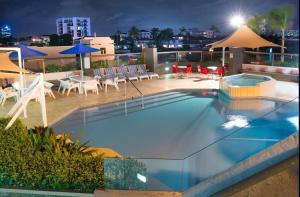 黄金海岸Tiki Hotel Apartments Surfers Paradise的一座大楼内的游泳池,配有椅子和遮阳伞