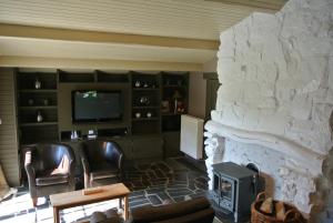巴斯托涅La Chaumière d'Alhoumont的客厅设有石制壁炉和电视。