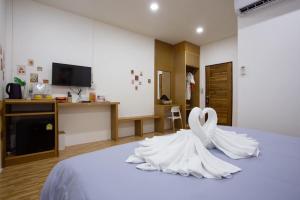 拉差汶里The Sun resort Ratchaburi的两只白天鹅坐在床上