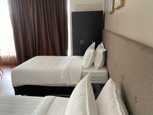 怡保King's Lane Ipoh的酒店客房,配有两张带白色床单和枕头的床