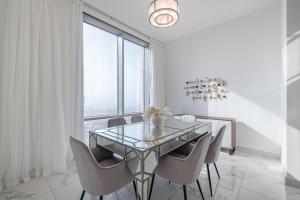迪拜Spacious 3BDR Apartment and maid room with Burj Khalifa View的一间设有玻璃桌和椅子的用餐室