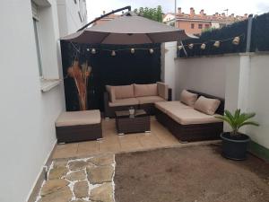 罗列特海岸Precioso apartamento con piscina y jardín propio的一个带沙发和遮阳伞的庭院