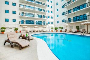 迪拜Golden Sands Suites的一座带椅子的酒店游泳池,一座建筑