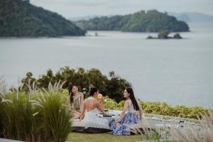 攀瓦海滩Amatara Welleisure Resort的三个妇女坐在湖边的桌子旁