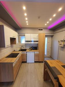 德布勒森Belvárosi Exkluzív Loft的厨房配有木制橱柜和紫色的天花板灯。