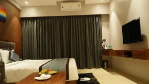 舍地Alaukik Hotel的酒店客房,配有床和电视