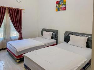 帕朗卡拉亚Nascar Family Hotel Palangkaraya Redpartner的两张床位于带窗户的房间内