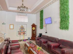 帕朗卡拉亚Nascar Family Hotel Palangkaraya Redpartner的客厅配有红色皮革沙发和时钟