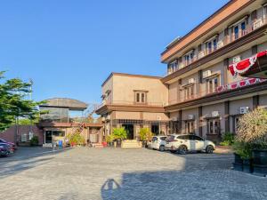 帕朗卡拉亚Nascar Family Hotel Palangkaraya Redpartner的两辆车停在停车场的大楼