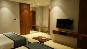 舍地Alaukik Hotel的配有一张床和一台平面电视的酒店客房