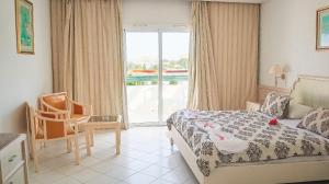 苏塞Hotel Royal Jinene Sousse的卧室配有床、椅子和窗户。