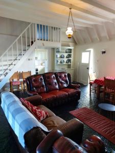 CorrofinCorofin Lake Cottages的客厅配有棕色皮革家具和楼梯