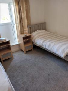 波斯考尔2 bedroom cottage in Porthcawl的卧室配有一张床,窗户旁设有床头柜