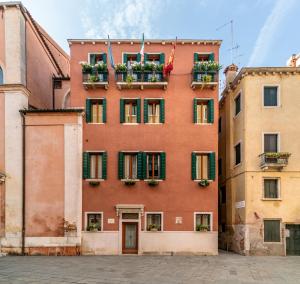 威尼斯圣卢卡宫住宿加早餐旅馆的红色的建筑,设有绿色百叶窗和花盒