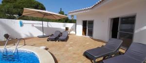 卡武埃鲁Casa Gemeas的一个带椅子和遮阳伞的庭院和一个游泳池