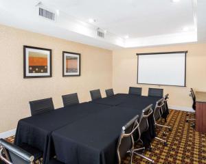 欧文Quality Suites Las Colinas Center的一间会议室,配有桌椅和屏幕