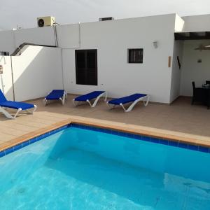 普拉亚布兰卡Villa julima的一个带2把蓝色椅子和桌子的游泳池