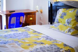 卡巴莱Kigezi Gardens Inn的一张带黄色和蓝色毯子的床和一张书桌