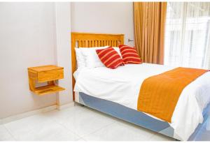 哈拉雷R Executive Apartments的一间卧室配有红色和橙色枕头的床