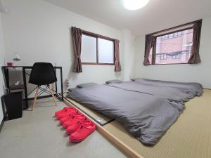 京都酷图斯戴旅馆的卧室配有一张带红色枕头的床,位于地板上
