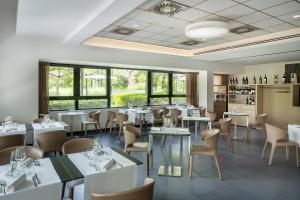 博洛尼亚UNAHOTELS Bologna Fiera的餐厅设有白色的桌椅和窗户。