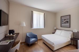 博洛尼亚UNAHOTELS Bologna Fiera的酒店客房配有一张床、一张桌子和一把椅子。