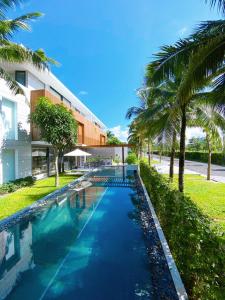 富国Phoenix Pool Villa Phu Quoc的棕榈树建筑前的游泳池