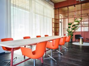 科隆STAYERY Köln Ehrenfeld的一间会议室,配有长桌子和橙色椅子