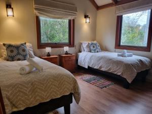 瓦尔迪维亚Hostel Torobayo的一间卧室设有两张床和两个窗户。