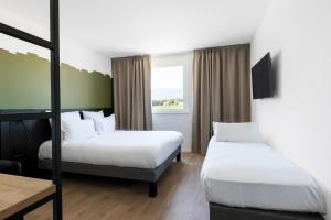 日内瓦B&B HOTEL Geneva Airport的酒店客房设有两张床和窗户。