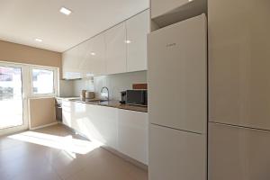 波尔图Apartamento da Musica - Boavista - OPENING的厨房配有白色橱柜和冰箱。