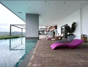 雪邦FREE PARKING # 2 Bed Family BellSuite - Sepang KLIA Kota Warisan的一座带紫色椅子和游泳池的房子