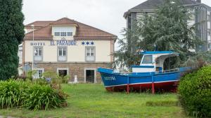 索托德尔瓦尔科Hotel El Parador的蓝船坐在建筑物前面的草上