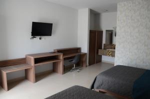 维多利亚城HOTEL MONARCA的酒店客房配有一张床、一张书桌和一台电视。