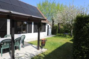 德帕内Bergh & Duin - lakens, elektriciteit en water inbegrepen的一座房子,设有两个绿色长椅和太阳能屋顶
