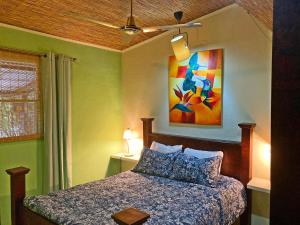 奥罗西Montaña Linda Hostel Orosi的卧室配有一张床,墙上挂有绘画作品