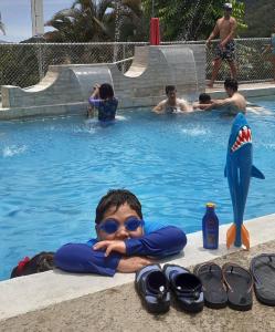 奥罗西Montaña Linda Hostel Orosi的一名男孩躺在游泳池里,手臂交叉