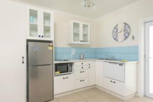 拉罗汤加Vaima Beachfront Apartments的厨房配有白色橱柜和冰箱。