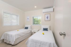 拉罗汤加Vaima Beachfront Apartments的配有2张床的白色墙壁和窗户客房