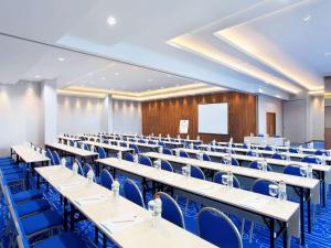 万隆万隆亚非宜必思快捷酒店的一个带桌子和蓝色椅子的大型讲座大厅