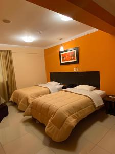 利马Royal Garden Hotel的橙色墙壁的酒店客房内的两张床