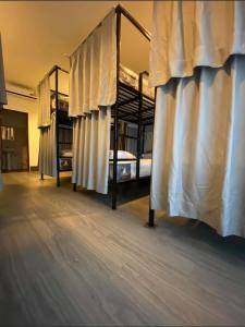 万象HideSeek Hostel Vientiane Thai embassy的客房设有带窗帘的两张双层床。