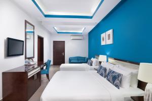 锡卜Al Hail Waves Hotel Managed By Centara的酒店客房,设有床铺和蓝色的墙壁