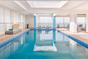 锡卜Al Hail Waves Hotel Managed By Centara的大楼内一个蓝色的大型游泳池