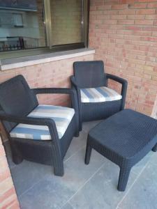 阿尔玛桑Apartamento El Prado的砖墙旁的两把藤椅和凳子