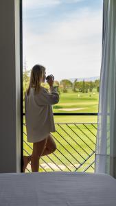 纳瓦拉Hotel TorreMirona Golf & Spa的一位女士通过窗户拍照片