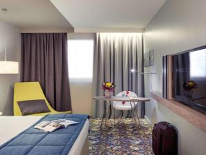 丰特奈苏布瓦巴黎巴尔德特奈美居酒店的一间酒店客房,配有一张床铺、一张桌子和一台电视