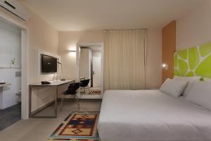 耶鲁姆Desert Iris Hotel的酒店客房配有一张床、一张书桌和一台电视。